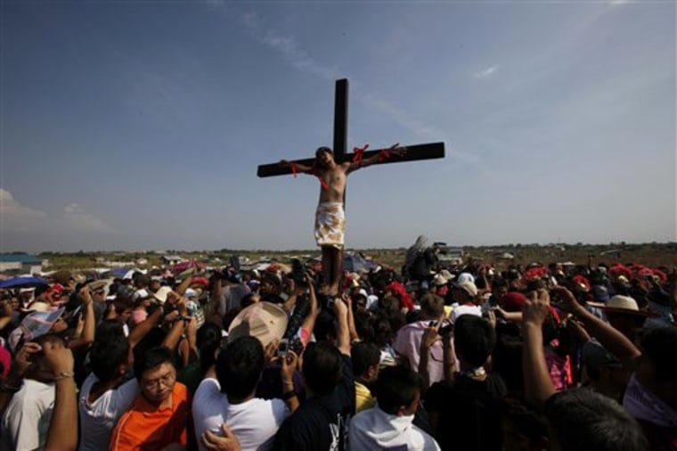 A crowd watches as Victor Caparas hangs by nails on a cross in a re-enactment of the crucifixion of Jesus Christ on Good Friday at Cutud village, San Fernando city, Pampanga province, northern Philippines.